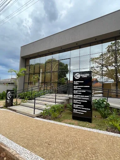 Fachada contemporânea da Galileo Clinic em Ituverava, com vidro, paisagismo e entrada por rampa.